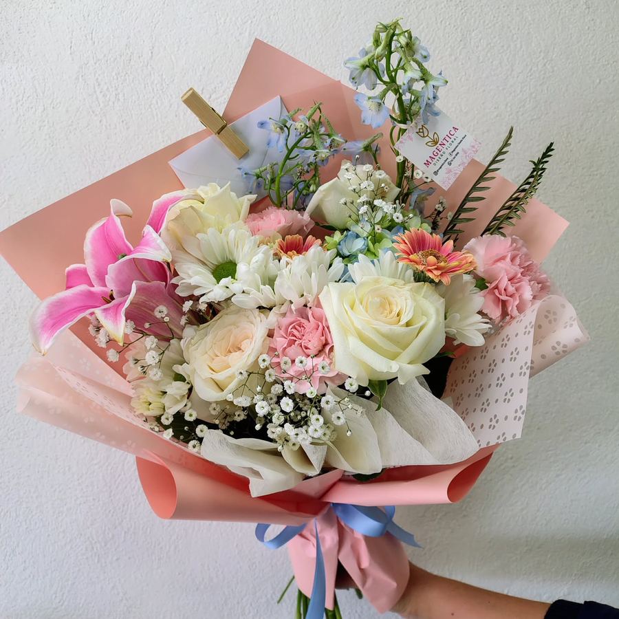 Ramo con lili rosa, rosas blancas, margaritas, claveles rosas y nube, en papel rosa con listón azul